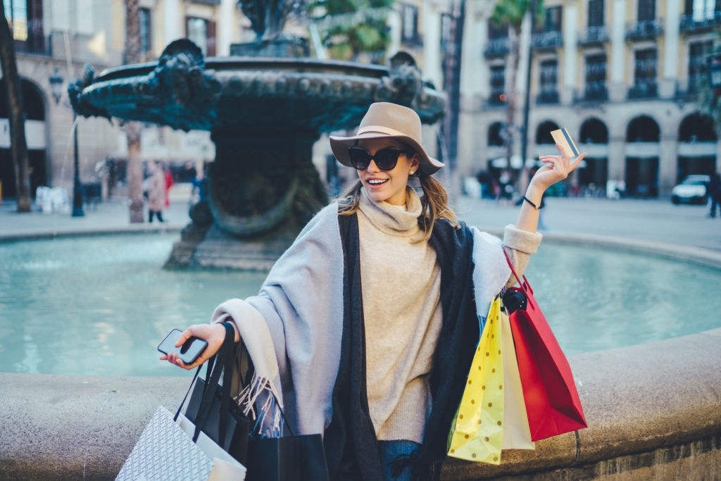 Rear view of woman taking photo of friend after shopping - Latest Fashion & Lifestyle Trends Best credit card for travel insurance