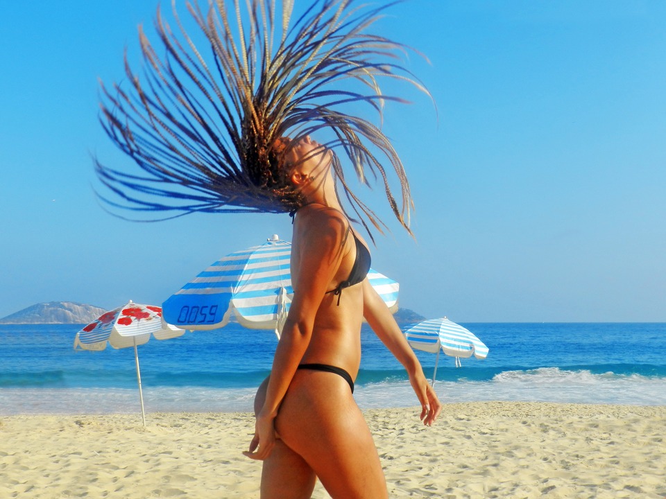 girl on the beach flipping her box braids