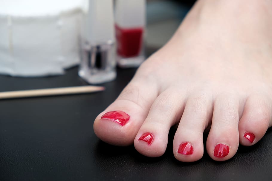 a picture of woman's feet with red nail paint on toe nails