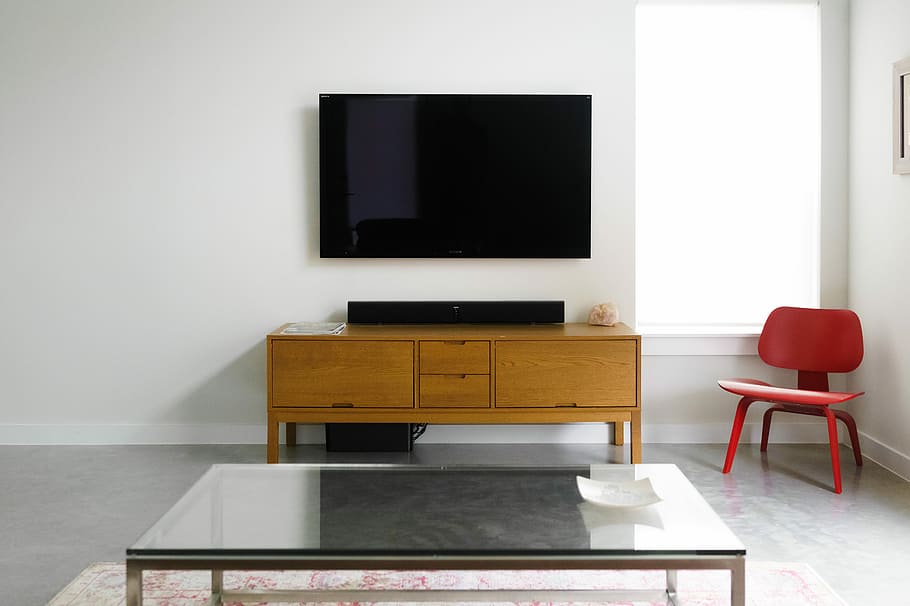 Tv mounted on a white wall in a room with table and red chair