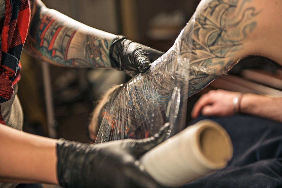 tattoo-artist-wrapping-client-s-arm-in-plastic-clingfilm-to-encourage-tattoo-healing - Latest Fashion & Lifestyle Trends