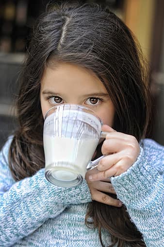 small girl drinking milk from glass